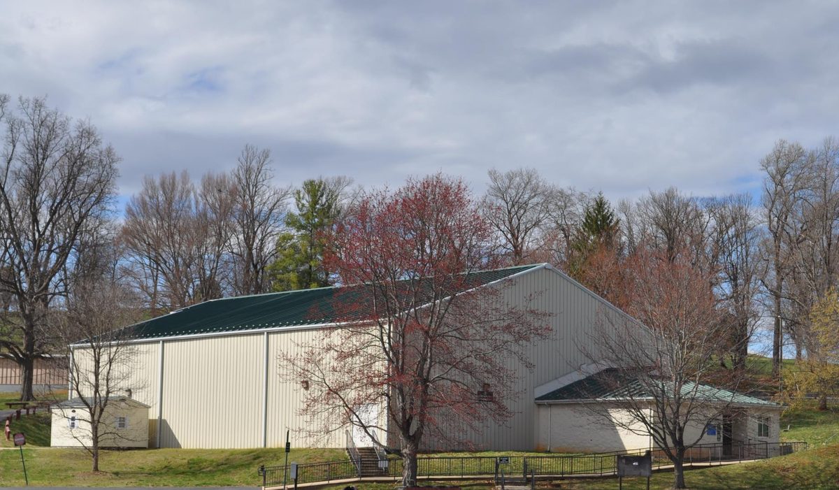 The cream metal Gypsy Hill Park Gym building with a green roof, seen from the parking lot.