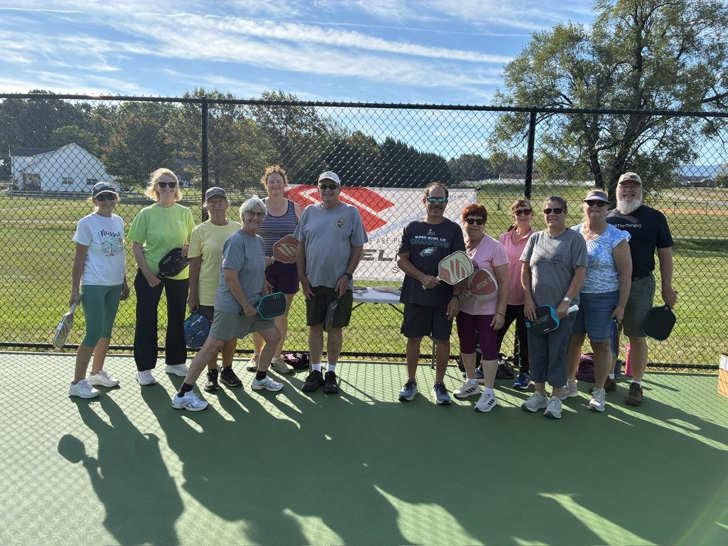 Participants holding paddles on the pickleball courts at Stuarts Draft Park after SVP's Introduction to Pickleball clinic.